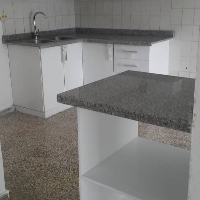 Cocina con gabinetes blancos y tope de granito