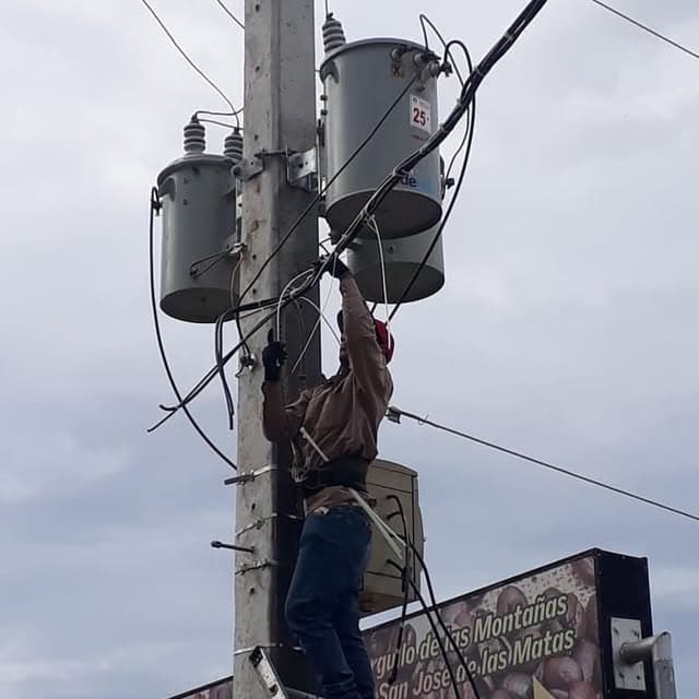 Técnico eléctrico trabajando en un poste del tendido